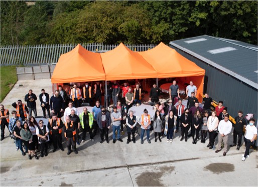 All of the Prima Cheese team standing in front of an orange marquee